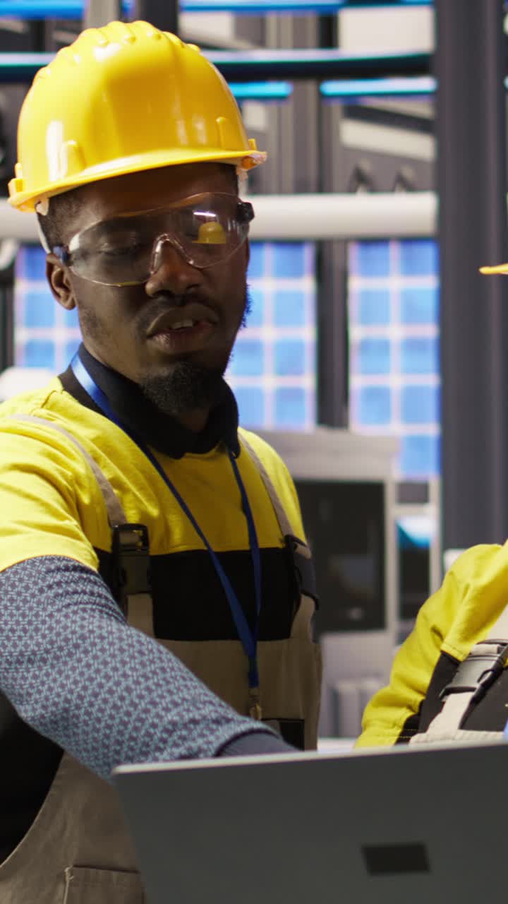 Vertical video Solar panels plant engineering team using laptop to oversee machinery systems