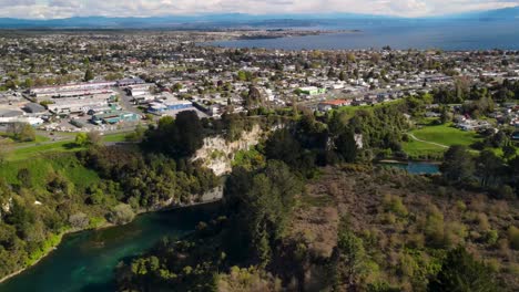 taupo, town and lake aerial scenic cityscape tilt down to waikato river, new zealand