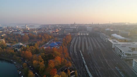 aerial, rising, drone shot, following a train entering the railway station, near kaivopuisto and helsinki cathedral, on a autumn evening, in helsingfors, finland