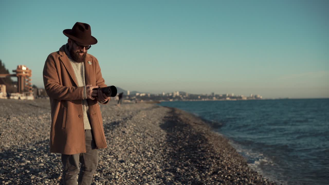 성인 남자는 은 추운 날씨에 해변에서 카메라로 사진을 찍고 있습니다.