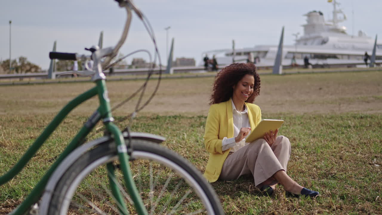 Woman Using Tablet with Bicycle in Park