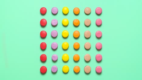 Macarons-Kekse-Bewegen-Sich-Auf-Farbigem-Hintergrund,-Draufsicht,-Stop-Motion-Animation