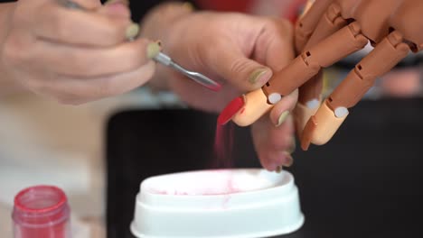 las manos femeninas pintan con uñas postizas de barniz rojo pegadas a una mano protésica 4k