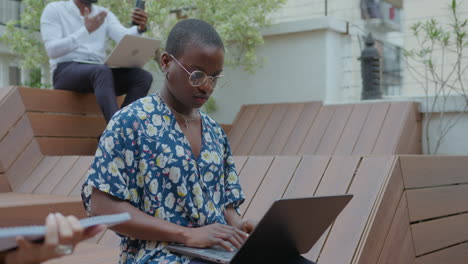 young black girl working on laptop at outdoor coworking space