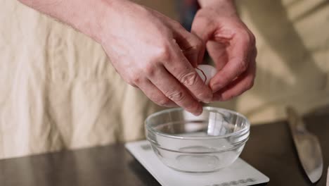 male hands cracking an egg in a bowl and separating egg white from yolk