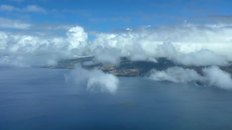 aerial view of madeira island and the funchal airport, taken at 1000m high from a jet cockpit during the approach, in a beautiful summer day with some clouds over the mountains