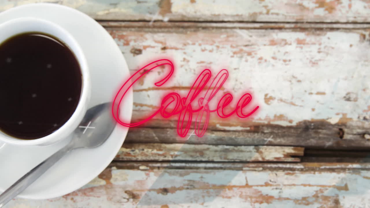 White ceramic coffee cup with saucer being placed on rustic wooden table, glowing neon coffee text