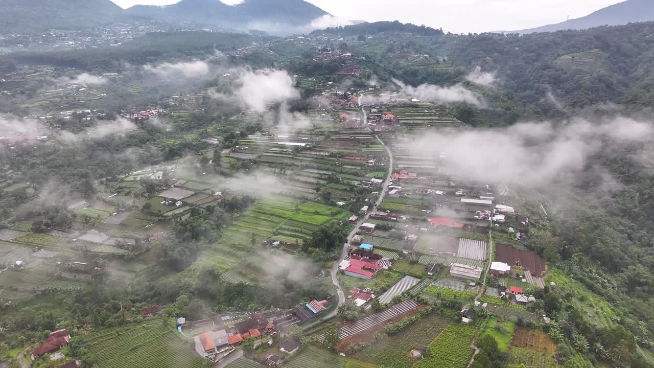 Dramatic view of farming village in rural Bali covered in mist. Indonesia landscape.