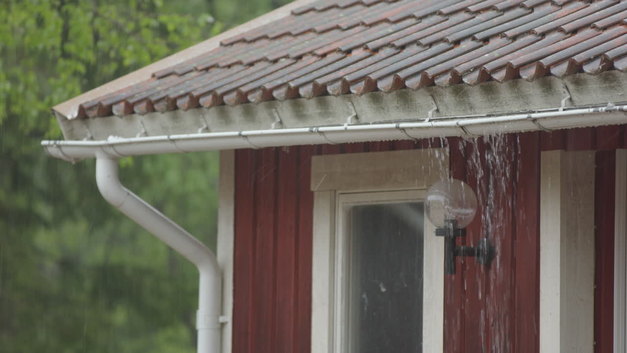 CLOSEUP - heavy rain on the roof causes the gutter to overflow