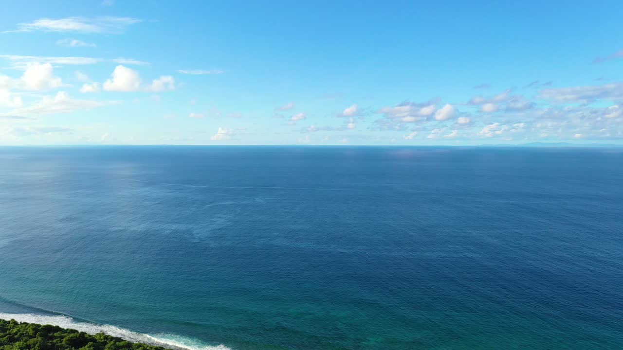 Drone footage of a tropical coastline, vibrant turquoise waters crashing into golden sand, lush greenery lining the shore, creating a perfect paradise travel and nature stock video