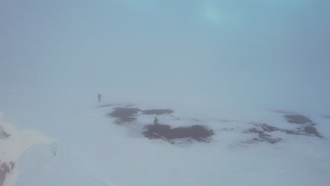 toma rápida en órbita aérea de fotógrafos en la cima de una montaña nublada, durante el sol de medianoche en noruega, y luego se desvanece