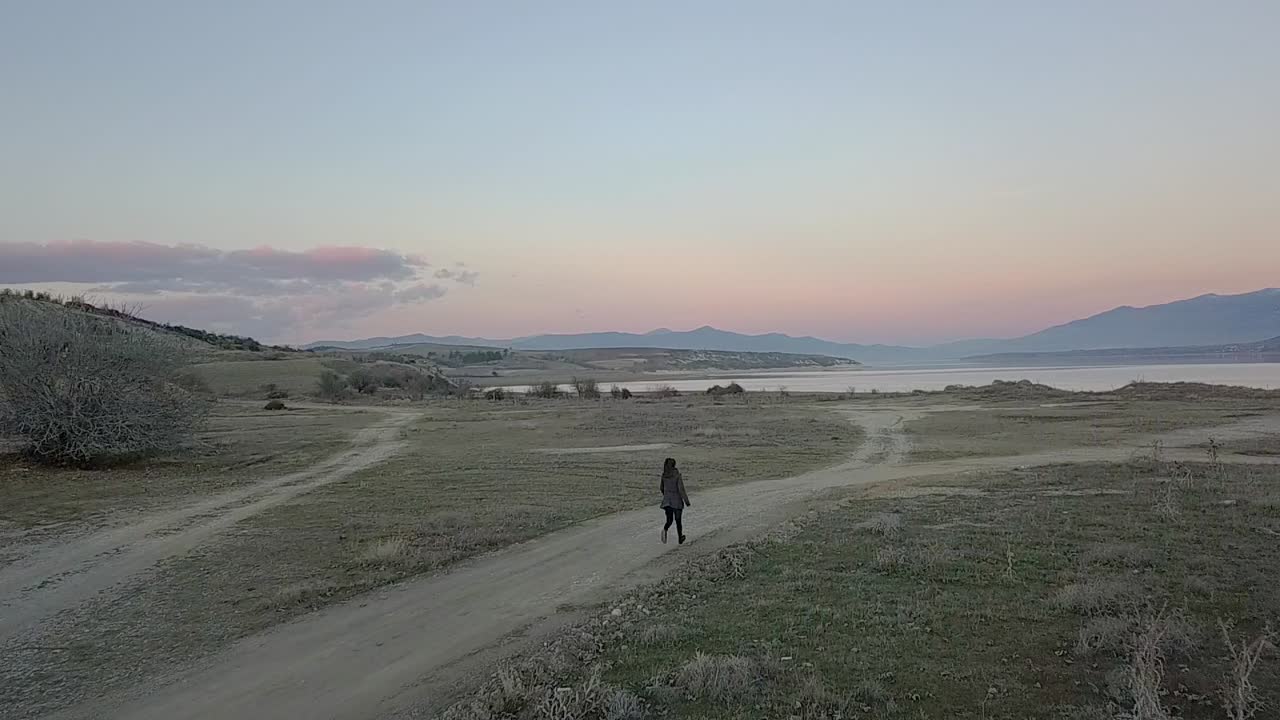 호수로 달려가는 소녀의 전방 드론 샷