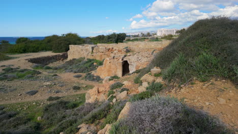 las ruinas de las tumbas de los reyes en pafos, con antiguas paredes de piedra y una entrada arqueada