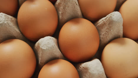 Video-of-close-up-of-brown-eggs-in-egg-carton-background