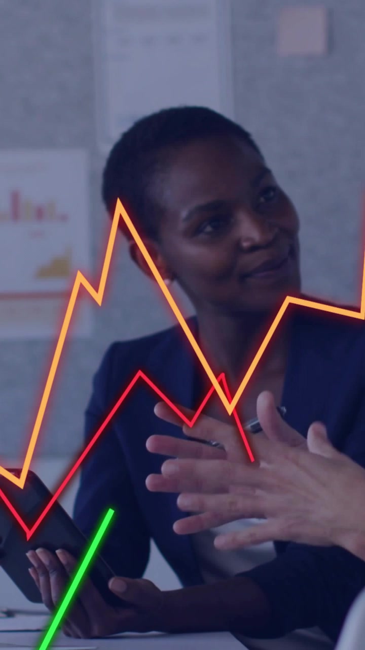 Vertical video: Lead woman with tablet while peer pointing, causing overlaying graphs showing KPIs