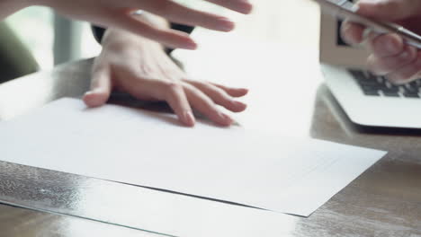 Mujer-Caucásica-Firmando-Un-Contrato,-Manos-Cerca-De-Una-Mujer-De-Negocios-Que-Trabaja-En-La-Oficina