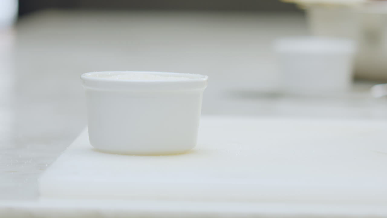 Close-up of a chef placing a ceramic mold on a chopping board. In the background, softly blurred, an aluminum mold can be seen