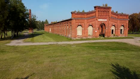 aerial view of former russian tsar army gymnastics hall in karosta, liepaja, used for gymnastics performances and competitions for horseback riders, wide angle ascending drone shot moving forward