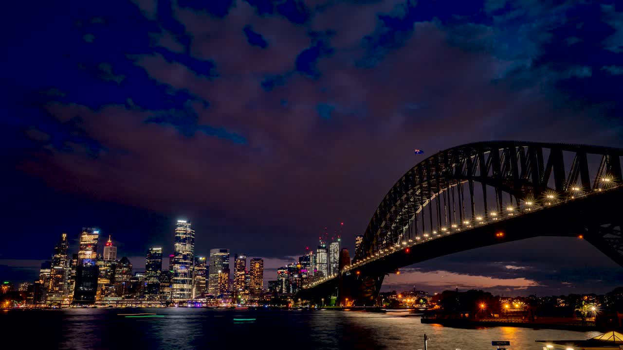 Wide Day to night time-lapse of Sydney Harbour Bridge and City Skyline during Vivid festival of lights