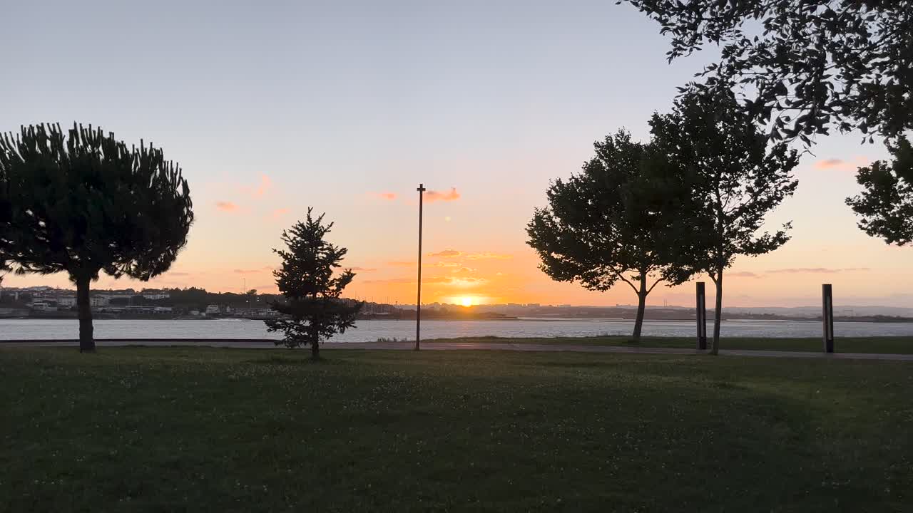 summer sunset in Lisbon, seen from the south bank on a windy day, with golden hues reflecting over the Tagus River.