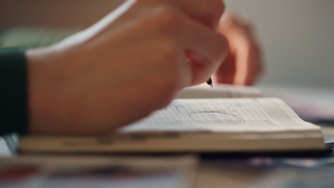 Girl hands making notes in notebook at workplace close up. Student crossing text