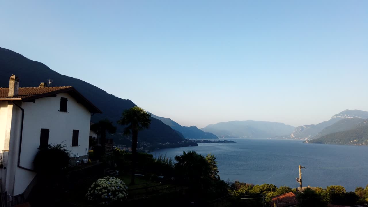 Timelapse orizzontale del Lago di Como in Italia, che mostra le calme acque del lago e le montagne sotto un cielo sereno con luce diurna costante