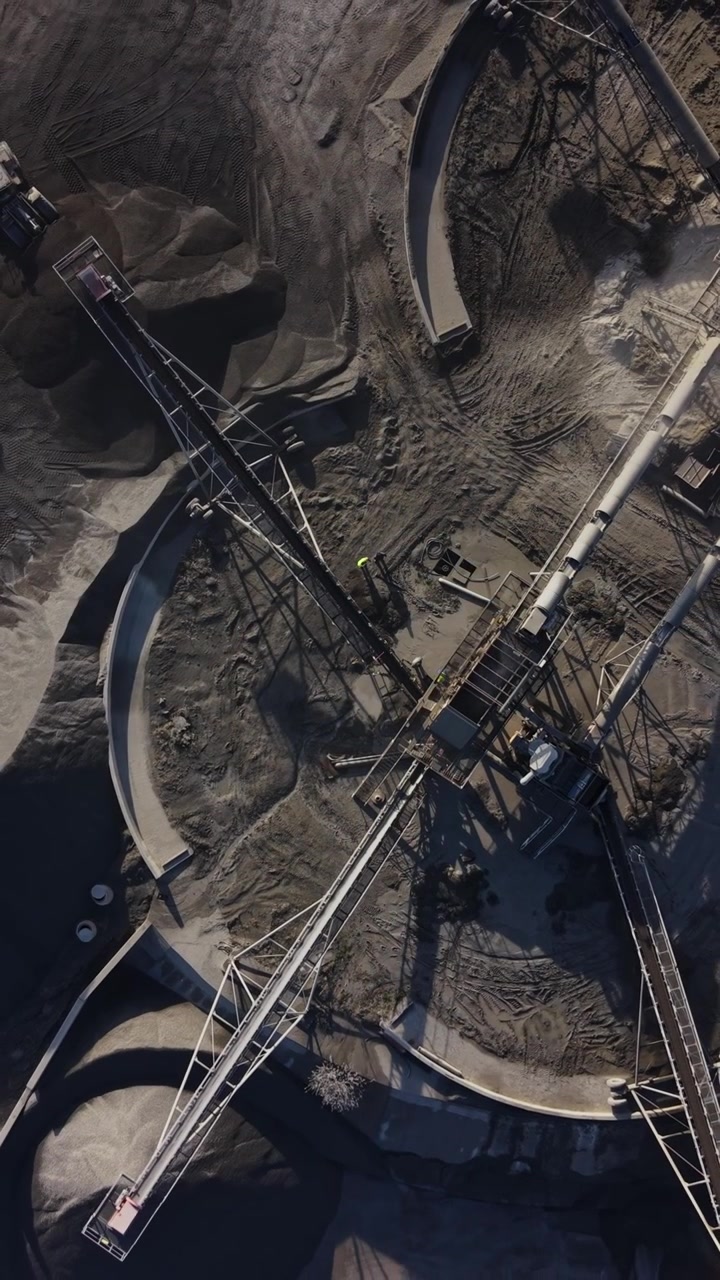 Quarry site showing mining equipment and stockpiles during daylight hours