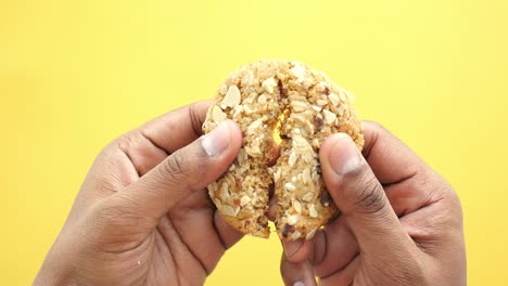 hands holding a broken oatmeal cookie with almonds