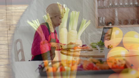 biracial woman in hijab chopping vegetables in kitchen, cooking over vegetables