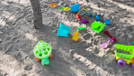 brightly colored toys scattered on a sandy beach in phuket, thailand, under natural sunlight, creating a playful and vibrant scene