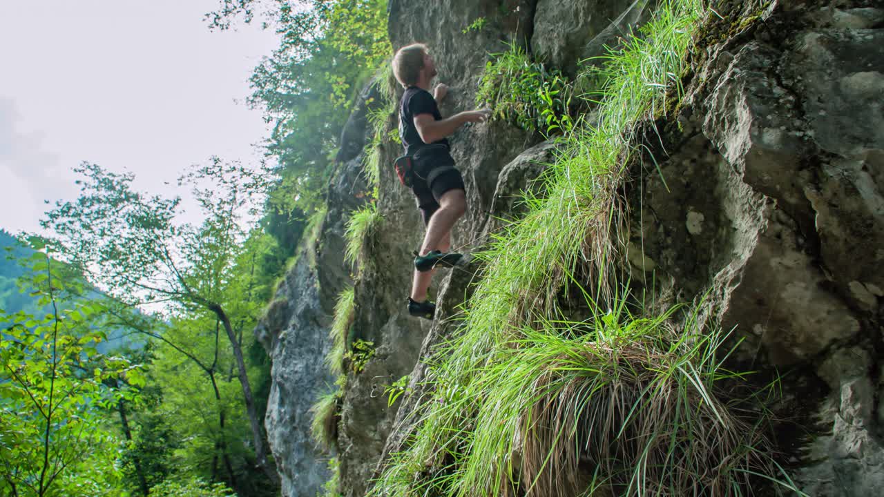 Young adventurous man, bouldering outdoors on steep rocks without any ropes