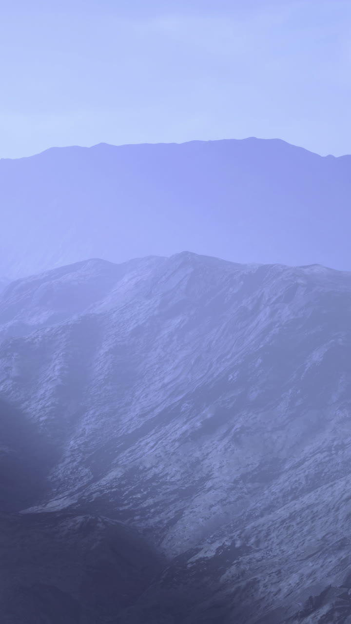 Gentle blue fog blankets the rugged mountain peaks