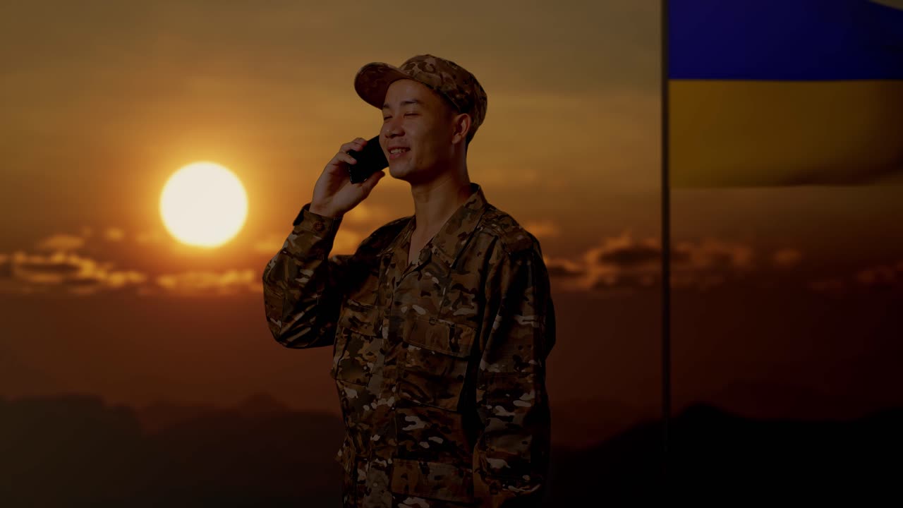 Soldato al telefono durante il tramonto con la bandiera ucraina
