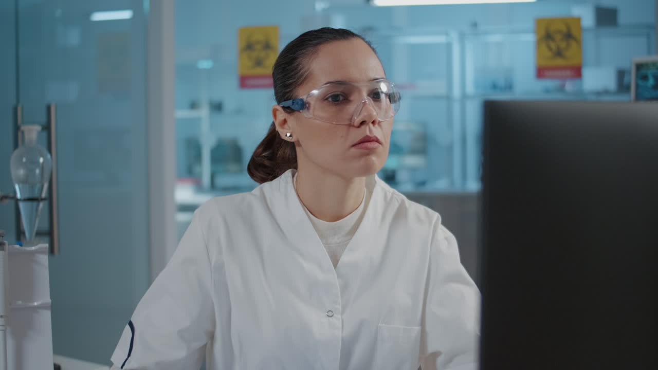Woman chemist taking notes and using computer for experiment
