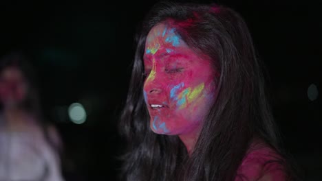 dancing young indian woman with dry color powder holi exploding around her