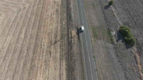 aerial top down shot following a vehicle on the road tilts up to reveal a barren drought affected landscape of farmland and fields, in stanthorpe australia