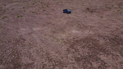 a 4x4 jeep toy truck drives fast, approaching from a leading shot and over rough terrain as seen from high aerial angle