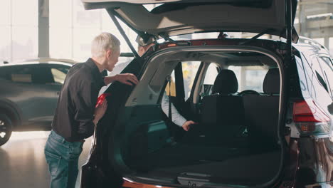 customer and salesperson inspecting car trunk