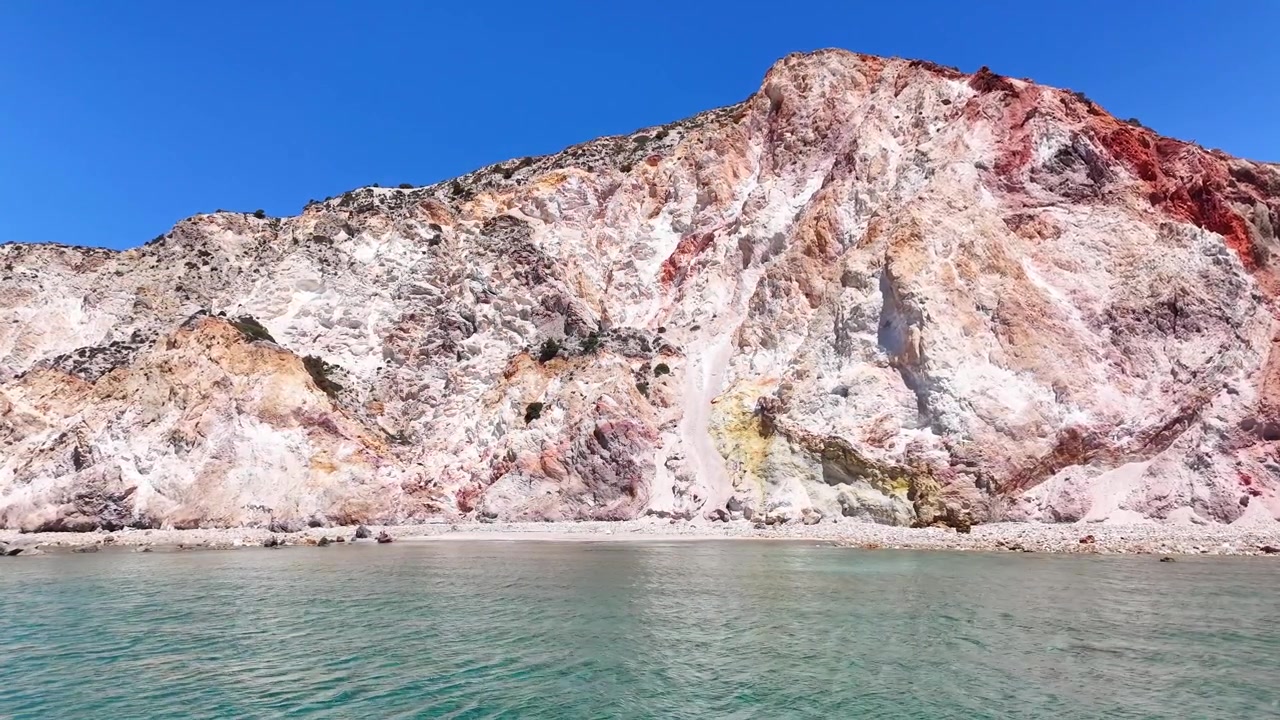 La playa de Firiplaka está enmarcada por acantilados volcánicos multicolores y roca erosionada pálida a lo largo de la costa sur de Milos, municipio de Milos, Egeo Meridional, Grecia, Europa, con capas costeras expuestas