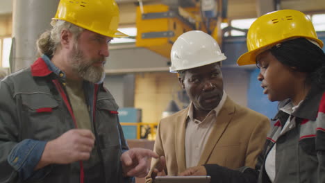 engineer using tablet and speaking with factory technicians