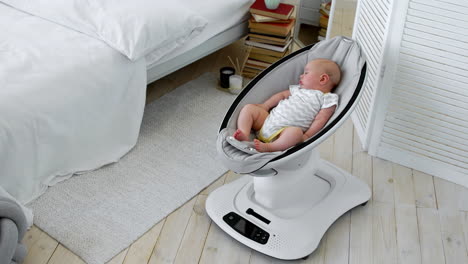 baby sleeps in a rocking chair for children high-tech design in white bedroom