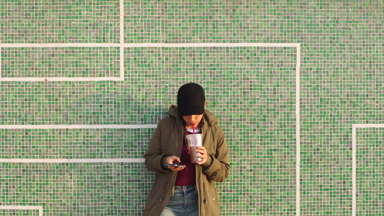 A woman relaxing against a tile wall using