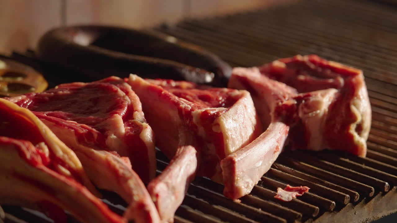 Hand Placing Raw Meat Steaks and Ribs on a Hot Grill
