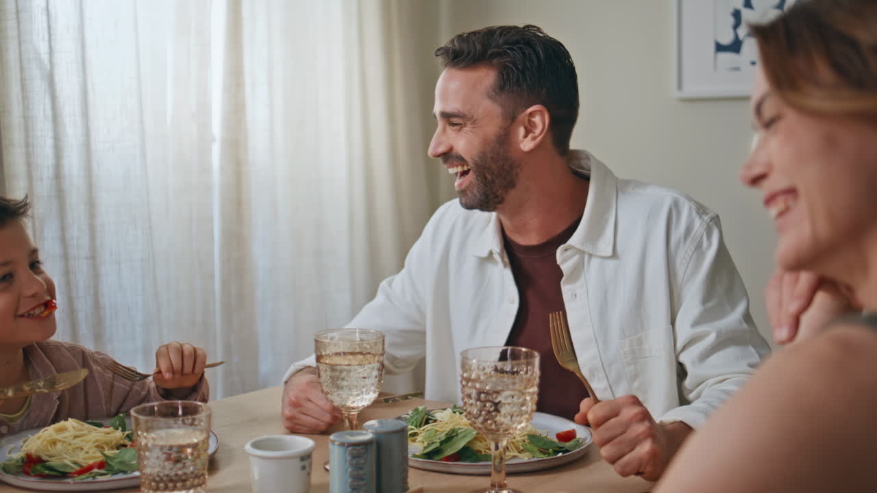 Laughing parents son eating at cozy kitchen closeup. Happy smiling family lunch