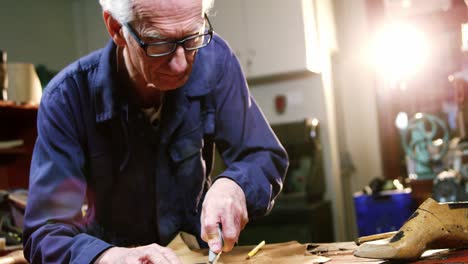 shoemaker cutting a piece of leather