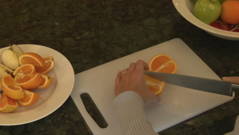 a woman slices oranges on a cutting board