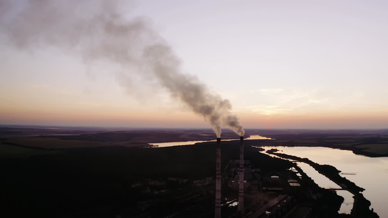 Industrial factory in nature in the evening. Chemical smoke from the factory chimneys. Concept of environmental pollution.