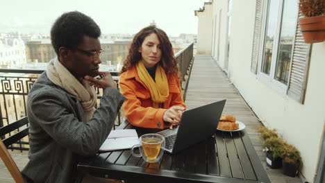 Diverse-Colleagues-Working-on-Laptop-in-Rooftop-Cafe