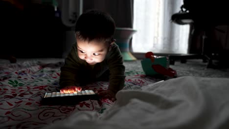 Adorable-6-Month-Old-Baby-Laying-On-Floor-Joyously-Interacting-With-LED-RBG-Light-On-Floor-In-Dark-Room