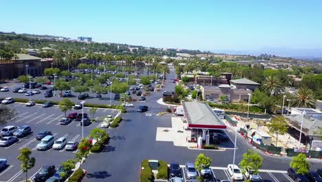 aerial fly through of a shopping mall parking lot over a gas station